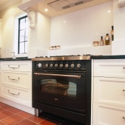 View of black oven set in cream kitchen cabinetry, countertop, cuisine classique, floor, flooring, home appliance, interior design, kitchen, kitchen appliance, kitchen stove, major appliance, oven, room, white