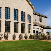 A view of some windows and doors by building, cottage, estate, facade, farmhouse, grass, home, house, lawn, mansion, property, real estate, residential area, siding, window, gray, brown