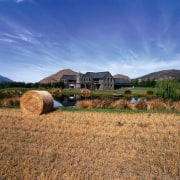 An exterior view of house with schist and agriculture, cloud, farm, field, grass, grass family, grassland, hay, highland, hill, home, house, landscape, mountain, plain, prairie, rural area, sky, straw, blue