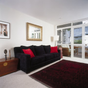 Dark sofa with red cushions in lounge room couch, floor, home, interior design, living room, property, real estate, room, window, gray, black