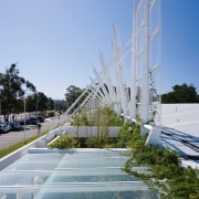 A view of the undulating canopy. - A architecture, building, corporate headquarters, daytime, landmark, reflection, residential area, sky, tree, water, teal, gray