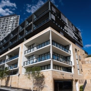 An exterior view of the apartments. - An apartment, architecture, building, commercial building, condominium, corporate headquarters, elevation, facade, home, mixed use, property, real estate, residential area, blue