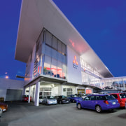 A view of the Mitsubishi Motors building. - architecture, building, car, commercial building, corporate headquarters, daytime, facade, luxury vehicle, metropolitan area, mixed use, sky, gray, blue