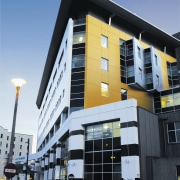 A view of a building that has Fletcher apartment, architecture, building, commercial building, condominium, corporate headquarters, facade, headquarters, home, house, metropolis, metropolitan area, mixed use, neighbourhood, property, real estate, residential area, window, teal, black