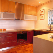 View of the kitchen featuring parquetry T&amp;G flooring, cabinetry, ceiling, countertop, cuisine classique, floor, flooring, hardwood, home, interior design, kitchen, orange, real estate, room, tile, under cabinet lighting, wood, wood flooring, brown, orange