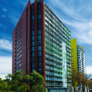 Two apartment complexes, one with red cladding, one apartment, architecture, building, city, commercial building, condominium, corporate headquarters, daytime, facade, headquarters, hotel, metropolis, metropolitan area, mixed use, real estate, residential area, sky, skyscraper, tower block, urban area, teal