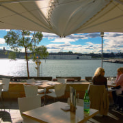 Waterfront seating area with tables and chairs, and resort, restaurant, vacation, water, brown, gray