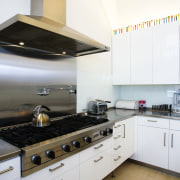 view of this kitchen featuring  travertie flooring, countertop, cuisine classique, floor, interior design, kitchen, kitchen stove, room, white