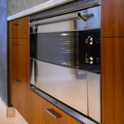 Closeup view of stainless steel oven set into cabinetry, countertop, furniture, home appliance, kitchen, major appliance, gray, brown