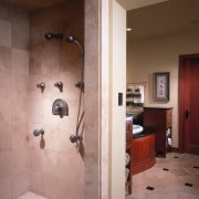 view of the bathroom featuring travertine and granite bathroom, door, floor, flooring, interior design, plumbing fixture, room, shower, tile, wall, brown, gray