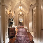 A corridor with a vaulted ceiling runs between aisle, arch, ceiling, chapel, column, estate, floor, flooring, hall, home, interior design, lobby, wall, brown