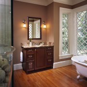 view of this bathroom featuring stained timber flooring, bathroom, bathroom accessory, bathroom cabinet, cabinetry, countertop, floor, flooring, hardwood, home, interior design, laminate flooring, room, sink, tile, wall, window, wood, wood flooring, brown