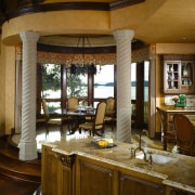 A view of this elegant kitchen featuring gold cabinetry, countertop, furniture, interior design, kitchen, room, window, brown