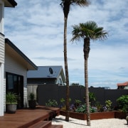 View of this outdoor enertainment area featuring landscaped agave, arecales, home, house, landscaping, outdoor structure, palm tree, plant, real estate, sky, tree, walkway, woody plant, white