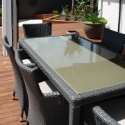 View of the outdoor dining area featuring table, chair, floor, flooring, furniture, outdoor furniture, table, wicker, black