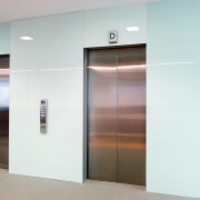 A view of the elevator lobby feauting glass door, elevator, glass, white