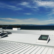 A view of a low pitched grey steel daylighting, deck, roof, sky, water, yacht, white