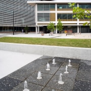 An exterior view of this building featuring metal architecture, asphalt, building, condominium, facade, house, residential area, road surface, roof, urban design, white