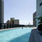 A view of the outdoor pool at the architecture, building, city, condominium, daytime, metropolitan area, reflection, sea, sky, skyscraper, swimming pool, vacation, water, teal