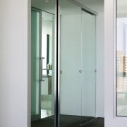 A view of the bedrrom featuring frameless mirrored door, glass, gray