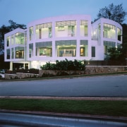 Exterior view of this house featuring a curved apartment, architecture, building, commercial building, condominium, corporate headquarters, estate, facade, home, house, mixed use, property, real estate, residential area, window
