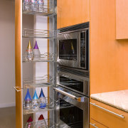 A view of this kitchen featuring stained timber cabinetry, closet, furniture, home appliance, kitchen, major appliance, room, shelf, shelving, orange, gray