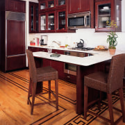 A view of this kitchen featuring cherry wood cabinetry, countertop, cuisine classique, dining room, floor, flooring, furniture, hardwood, interior design, kitchen, laminate flooring, room, table, wood, wood flooring, wood stain, red