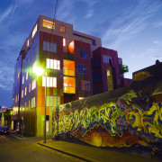 A view of this urban residential building implemented architecture, building, city, condominium, evening, facade, graffiti, house, landmark, metropolis, metropolitan area, mixed use, neighbourhood, night, real estate, residential area, sky, street, urban area, wall, yellow, blue, brown