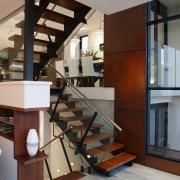 A view of the staircase featuring stainless steel floor, flooring, handrail, interior design, stairs, structure, gray, brown