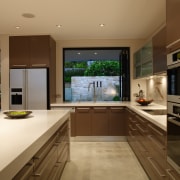 A view of the kitchen area featuring polished cabinetry, countertop, cuisine classique, interior design, kitchen, real estate, room, under cabinet lighting, brown