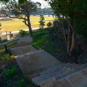 A view of the pathways and landscaped gardens backyard, grass, house, landscape, landscaping, outdoor structure, path, plant, road surface, tree, walkway, wall, yard, black