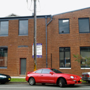 A view of this 1970s masonry warehouse with architecture, automotive design, building, car, city, facade, family car, home, house, luxury vehicle, motor vehicle, neighbourhood, property, real estate, residential area, sedan, vehicle, window, brown