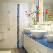 A view of this bathroom featuring white cabinetry, bathroom, bathroom accessory, bathroom cabinet, floor, interior design, plumbing fixture, room, sink, tile, wall, orange, gray