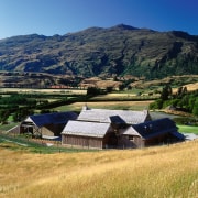 An exterior view of this rural farmstead house farm, fell, field, grass, grassland, highland, hill, home, house, hut, landscape, meadow, mount scenery, mountain, mountain range, mountainous landforms, national park, pasture, real estate, rural area, sky, sunlight, village, wilderness, blue