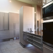 A view of this kitchen featuring tiled flooring, cabinetry, countertop, floor, home appliance, interior design, kitchen, gray, black, white