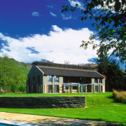 An exterior view of this rural home designed cottage, estate, facade, farm, farmhouse, grass, home, house, land lot, landscape, lawn, plantation, property, real estate, roof, sky, tree, villa