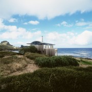An exterior view of this coastal property on cloud, coast, cottage, grass, home, horizon, house, promontory, real estate, sea, shore, sky, terrain, white