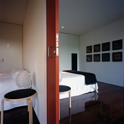 A view of the bedroom featuring  recycled architecture, bed, bed frame, ceiling, door, floor, furniture, interior design, light fixture, lighting, room, suite, wall, gray, black