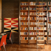 An interior view of the living areas featuring bookcase, bookselling, furniture, institution, interior design, library, library science, public library, shelf, shelving, wood, brown