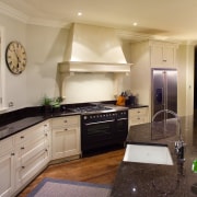 A view of this traditional kitchen featuring antique cabinetry, ceiling, countertop, cuisine classique, floor, flooring, home, interior design, kitchen, living room, real estate, room, wood flooring, orange
