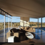 An interior view of the living area featuring architecture, ceiling, daylighting, house, interior design, living room, real estate, table, window, black, brown