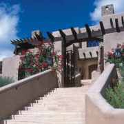 An exterior view of this Tuscan desert home, architecture, home, house, outdoor structure, property, real estate, roof, sky, wall, gray