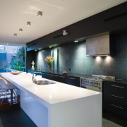 The gallery-style kitchen, which continues the strong horizontal architecture, countertop, house, interior design, kitchen, property, real estate, gray, black