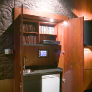 A cabinets hide a wall mounted touchpad fof cabinetry, furniture, interior design, room, wood, brown
