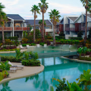 A view of these landscaped gardens and pool arecales, condominium, estate, home, landscaping, leisure, palm tree, property, real estate, residential area, resort, swimming pool, tree, villa