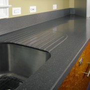 A view of this kitchen featuring the Corian countertop, floor, flooring, granite, kitchen, sink, gray, black