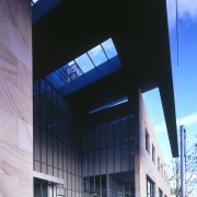 A deep overhead canopy covers the entrance to architecture, building, commercial building, corporate headquarters, daylighting, daytime, facade, glass, headquarters, house, mixed use, sky, structure, black, blue