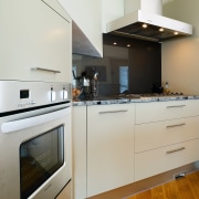 A view of this kitchen featuring the latest apartment, architecture, cabinetry, countertop, cuisine classique, floor, hardwood, home, home appliance, interior design, kitchen, kitchen appliance, kitchen stove, major appliance, room, wood, wood flooring, white