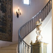 View of staircase, lighting, statue, wrought iron handrail. baluster, ceiling, estate, floor, handrail, home, interior design, light fixture, lighting, molding, stairs, wall, gray