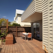 An exterior of this house featuring Merbau decking, deck, home, house, outdoor structure, real estate, residential area, siding, orange